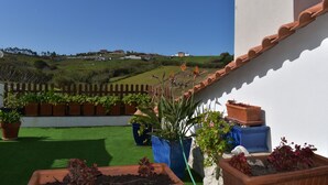 A rooftop garden with various potted plants, a view of a hillside, and a wooden fence. - Roof Top apartment, quiet, 2 large terraces, close to the best beaches (Lourinha)