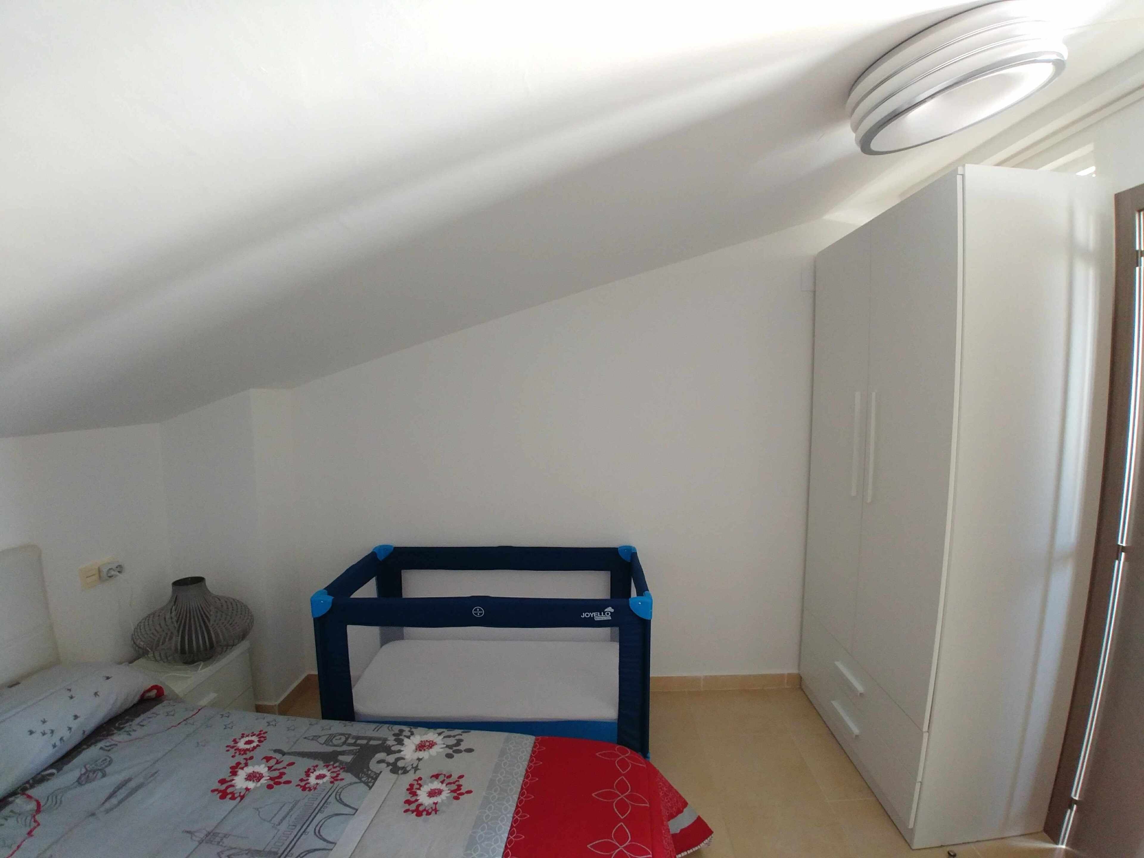 A small, well-lit room with a bunk bed, a white wardrobe, and a tiled floor.