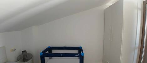 A small, well-lit room with a bunk bed, a white wardrobe, and a tiled floor.