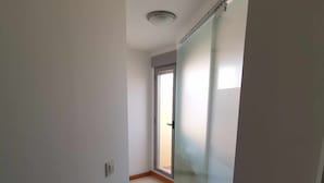 Un couloir étroit avec une porte-fenêtre coulissante donnant sur un balcon.