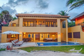 A two-story building with a swimming pool, outdoor seating, and a well-maintained lawn. - Top Class Luxury Beachfront Villa in Akumal With Chef Services. (Akumal)