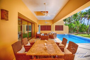 A poolside area with wicker furniture, a ceiling fan, and a view of the pool and greenery. - Top Class Luxury Beachfront Villa in Akumal With Chef Services. (Akumal)