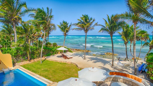 Een resort met een zwembad, ligbedden en parasols met uitzicht op de oceaan.