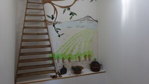 A wall with a ladder leading to a shelf holding shoes, potted plants, and a decorative item. - CHARMING GUEST GARDEN TERRACE SWIMMING POOL, FREE PARKING AND WIFI, BEACHES 8 Km away  (Pomérols)