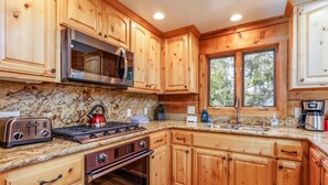 Una cocina con armarios de madera, microondas de acero inoxidable, estufa a gas, tostadora y cafetera.