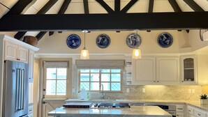 A kitchen with a large island, two barstools, a ceiling fan, and decorative plates on the wall. - 4-bedroom vacation home just 12 minutes from LEGOLAND® California (Oceanside)