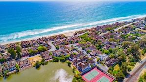 An aerial view of a coastal residential area with houses, a beach, and a tennis court. - 4-bedroom vacation home just 12 minutes from LEGOLAND® California (Oceanside)