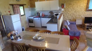 A compact kitchen with a dining area, a sofa, and a television. - Pretty Dordogne valley house, heated swimming pool sleeps 8 (7 adults max) (Nadaillac de rouge)