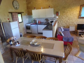 A compact kitchen with a dining area, a sofa, and a television.