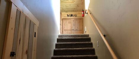 Una escalera de madera con barandilla acolchada que conduce a una puerta en la parte superior.