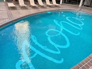Una piscina con bordo piastrellato e motivo blu sulla superficie dell'acqua.
