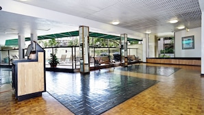 A spacious lobby with a reception desk, seating areas, and a green awning providing shade. - 2-Bedroom Vacation Rental in Waikiki (Honolulu)