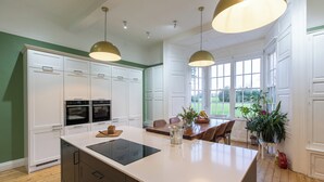 Une cuisine moderne avec des meubles blancs, un îlot central et des luminaires suspendus.