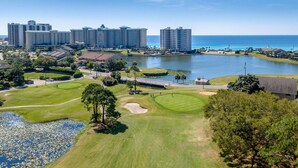 En golfbana med en sjö, omgiven av höga hotell och med fri utsikt över havet.