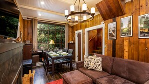 A cozy room with a wooden interior, a dining area with a table and chairs, and a comfortable brown sofa with a red rug. - Seattle Carriage House: Private Urban Retreat with Chickens (Seattle)