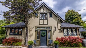 A two-story house with a front porch, a front door with a wreath, and two potted plants on either side. - Seattle Carriage House: Private Urban Retreat with Chickens (Seattle)