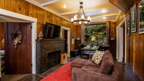 A cozy living room with a fireplace, a red rug, and a brown leather sofa. - Seattle Carriage House: Private Urban Retreat with Chickens (Seattle)