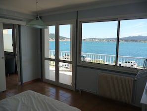 Ein Zimmer mit einem großen Fenster mit Blick auf ein Gewässer, einem Bett und einer Heizung.