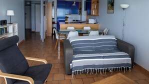 Ein modernes Wohnzimmer mit einer Couch, einem Holztisch und einem Essbereich mit Tisch und Stühlen.