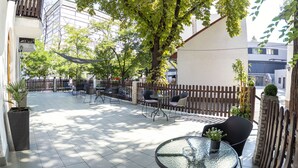 An outdoor patio with tables and chairs, surrounded by a wooden fence and potted plants. - Richter Pansion (Budapest)