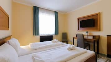 Habitación de hotel con dos camas, un escritorio, una silla, un televisor y una ventana con cortinas.