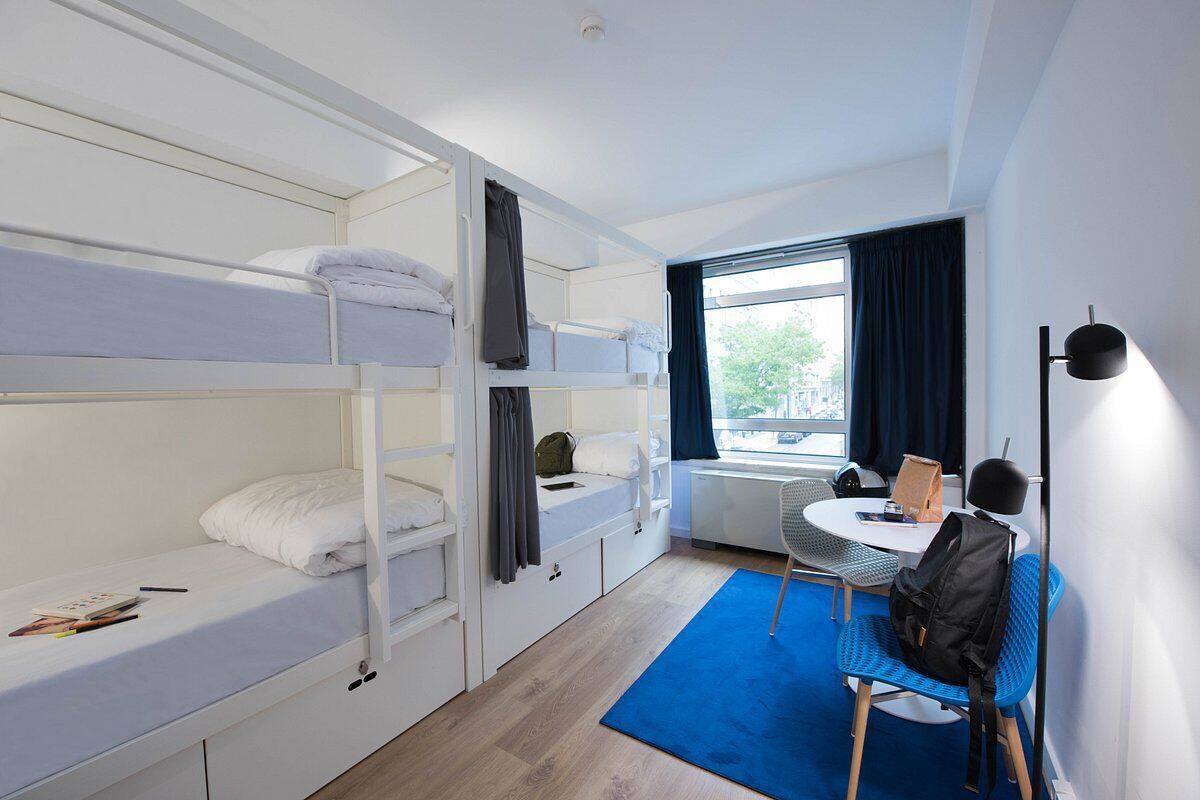 Habitación con literas, un escritorio, una silla, una ventana con cortinas y un radiador.