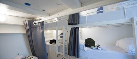 A bunk bed room with a curtain, a map, and a book on the lower bunk.