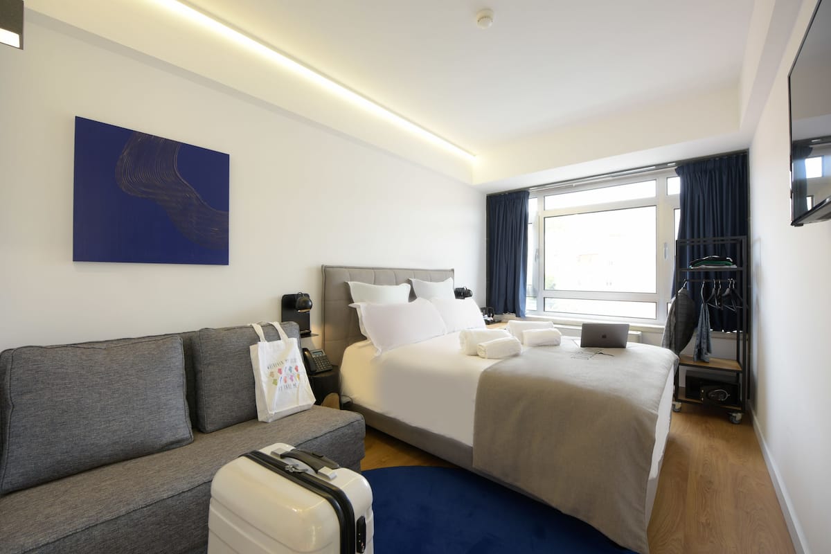 Una habitación de hotel con cama, sofá, escritorio y ventana.
