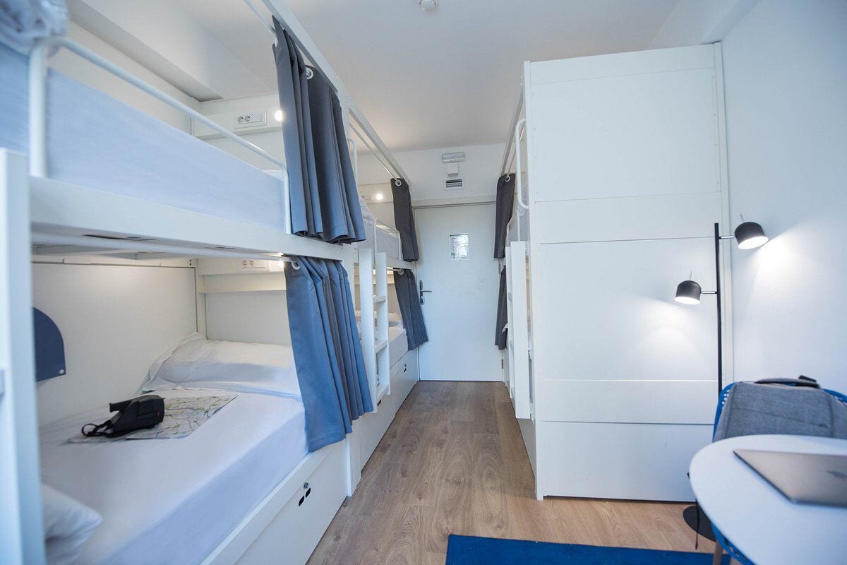 A compact hotel room with bunk beds, a desk, and a wardrobe.