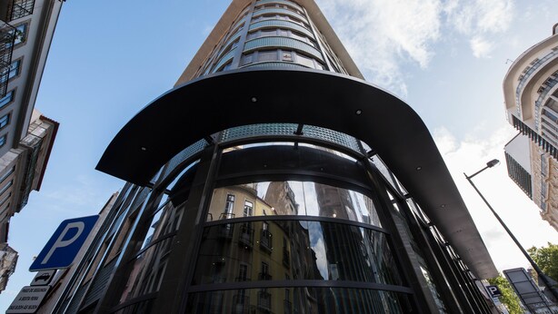 Un edificio moderno con una entrada curva y una señal de estacionamiento.
