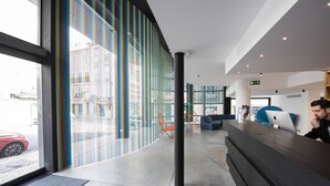 Un área de recepción moderna con un muro de cristal curvo, un mostrador de recepción y zonas de estar.