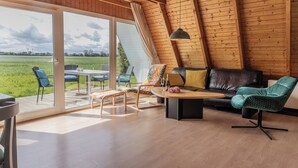 A spacious living area with a large sliding glass door leading to an outdoor deck, a black leather sofa, and a wooden coffee table. - Exceptional and unusual: The A-house with its ca. (Carolinensiel)
