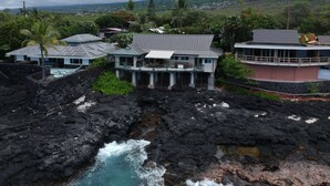 En fastighet vid kusten med en pool, flera byggnader och utsikt över havet och kullarna.