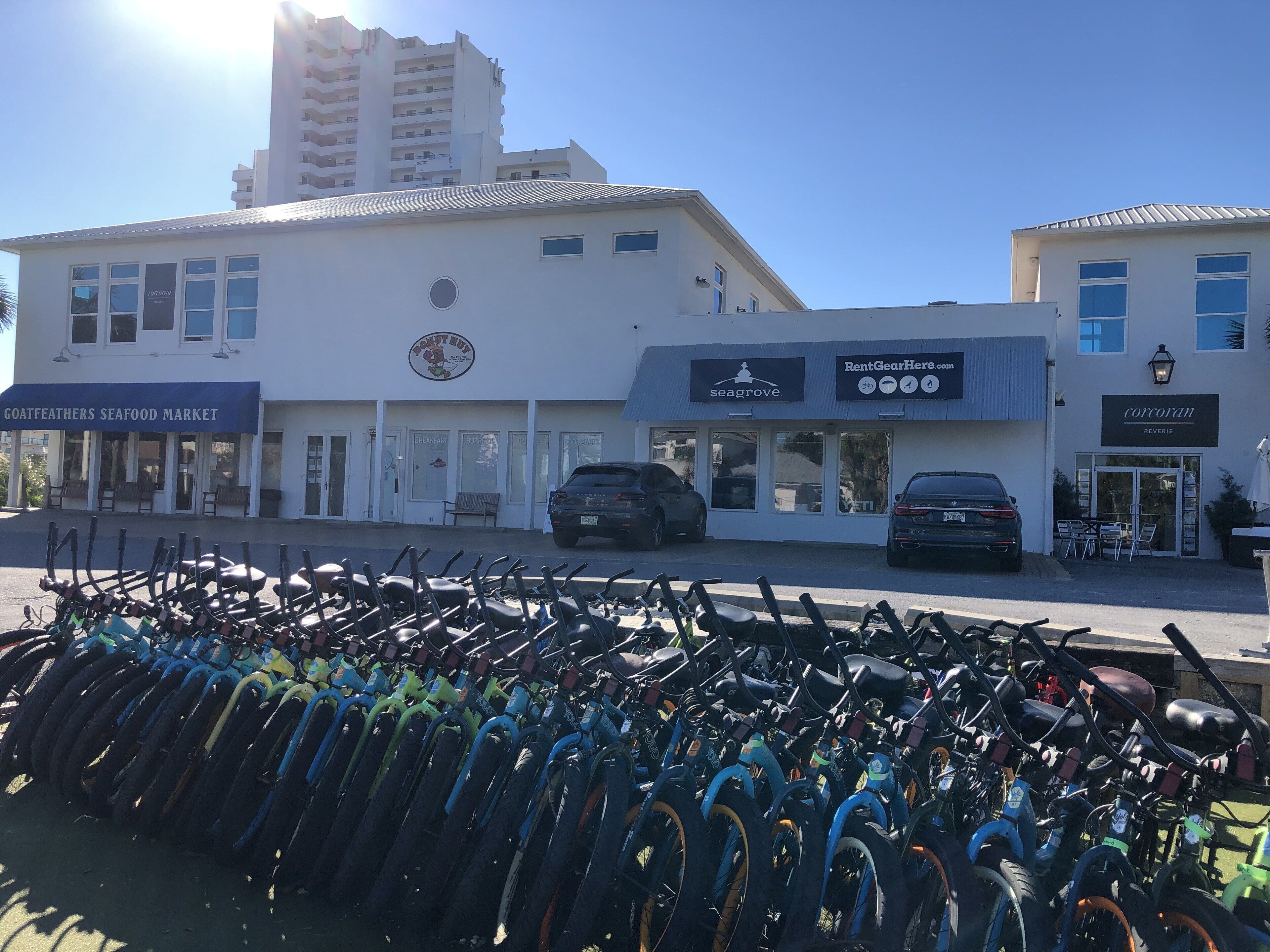 A building with multiple storefronts, including a seafood market and a rental gear store.