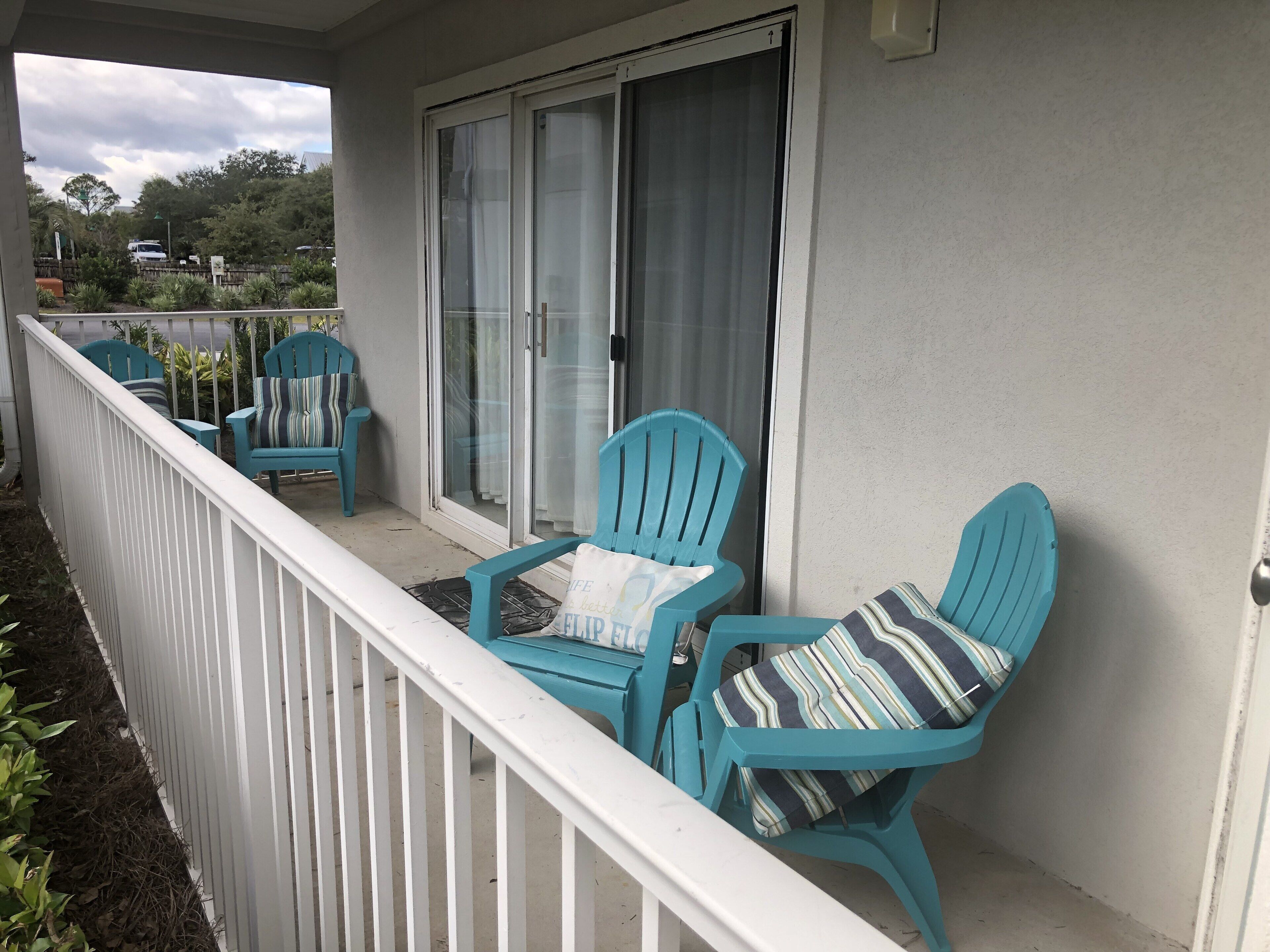 Een balkon met turquoise stoelen en een witte reling.