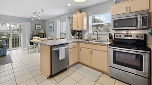 A modern kitchen with a central island, stainless steel appliances, and a dining area with a view. - Modern coastal 1st floor 30A unit w/ walkability to restaurants & beach! (Santa Rosa Beach)