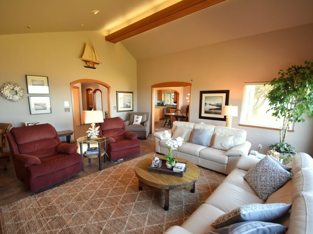 A spacious living room with a high ceiling, a fireplace, and a large window.