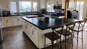 Una cocina moderna con armarios blancos, una isla grande y una zona de comedor con taburetes de bar.