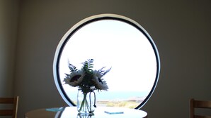 Una mesa redonda con un jarrón de flores frente a una ventana.