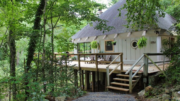 Ein Haus mit Holzterrasse, einer Treppe und Blick auf den umliegenden Wald.