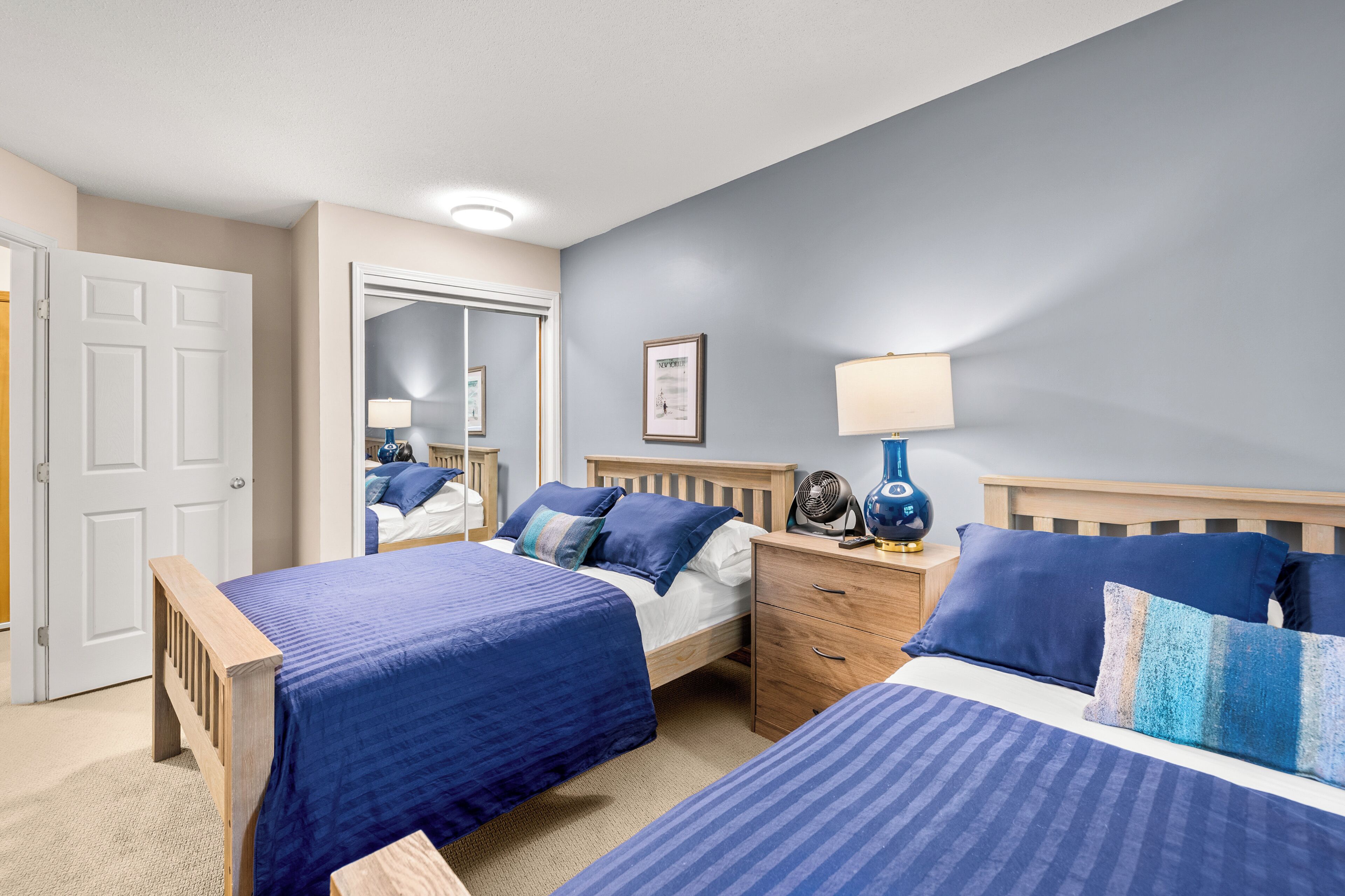 Une chambre avec deux lits, une table de chevet, une commode et un miroir.