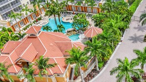 A resort with multiple swimming pools, palm trees, and a red-roofed building. - Enjoy Gorgeous Panoramic Views Of The Gulf Of Mexico And Vanderbilt Bay  (Naples)