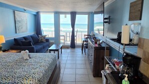 A room with a bed, a desk, a coffee maker, and a view of the ocean. - Brandy's Direct Ocean View Over The Large Heated Pool & Hot Tub, Sleeps 4 (Daytona Beach)