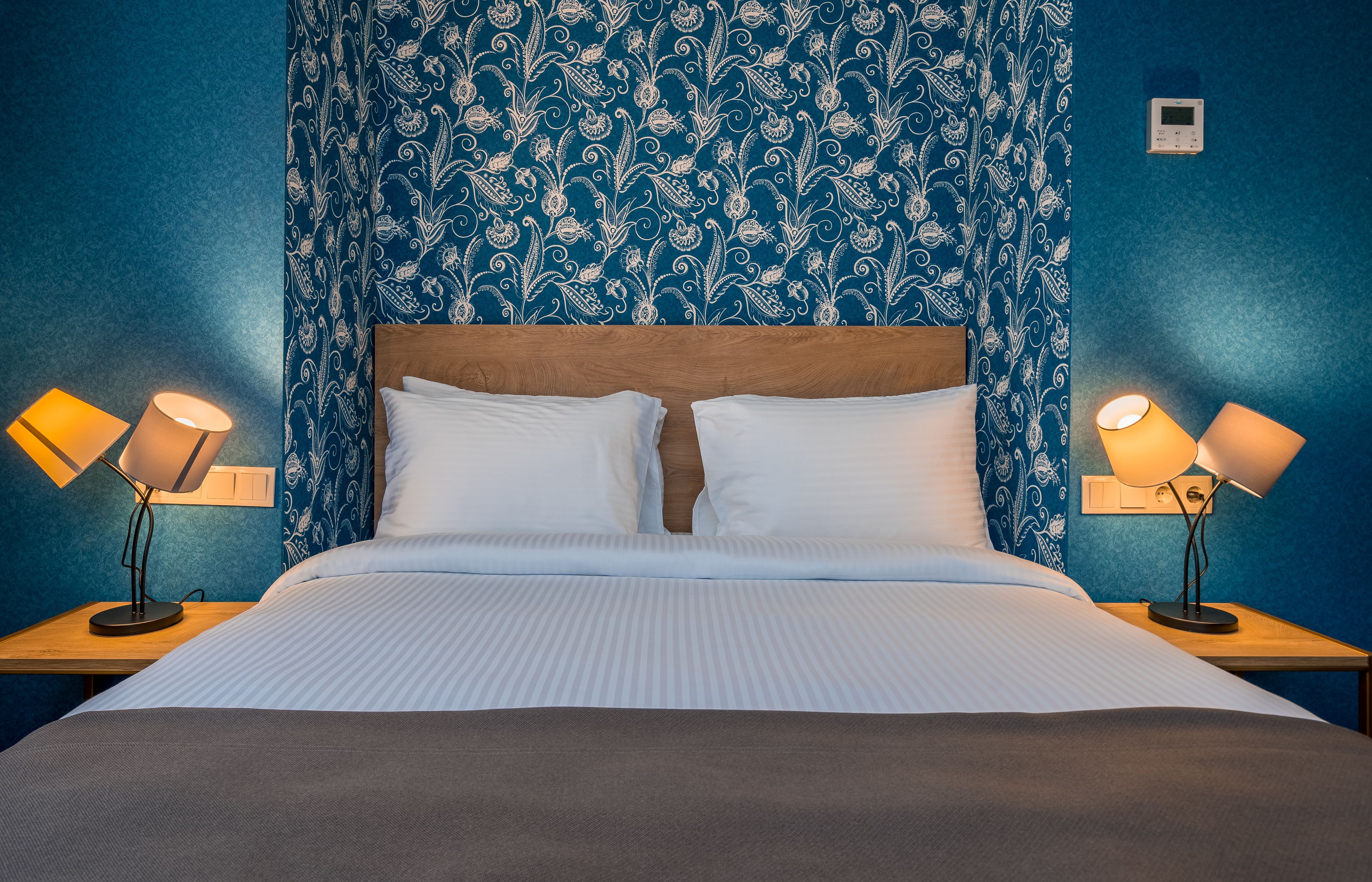 A neatly made bed with white linens and two bedside lamps on wooden nightstands.