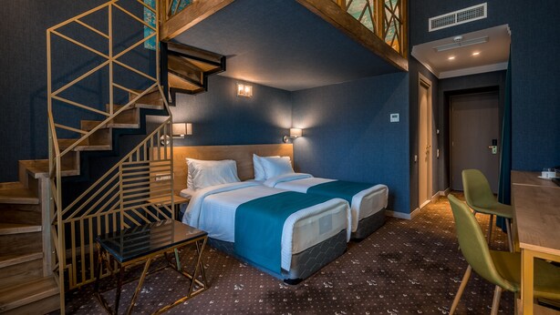 A bedroom with two beds, a staircase, a desk, and a chair. - Hotel Gladius inn (Tbilisi)