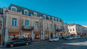 A street with buildings, cars, and a pedestrian. - Hotel Gladius inn (Tbilisi)