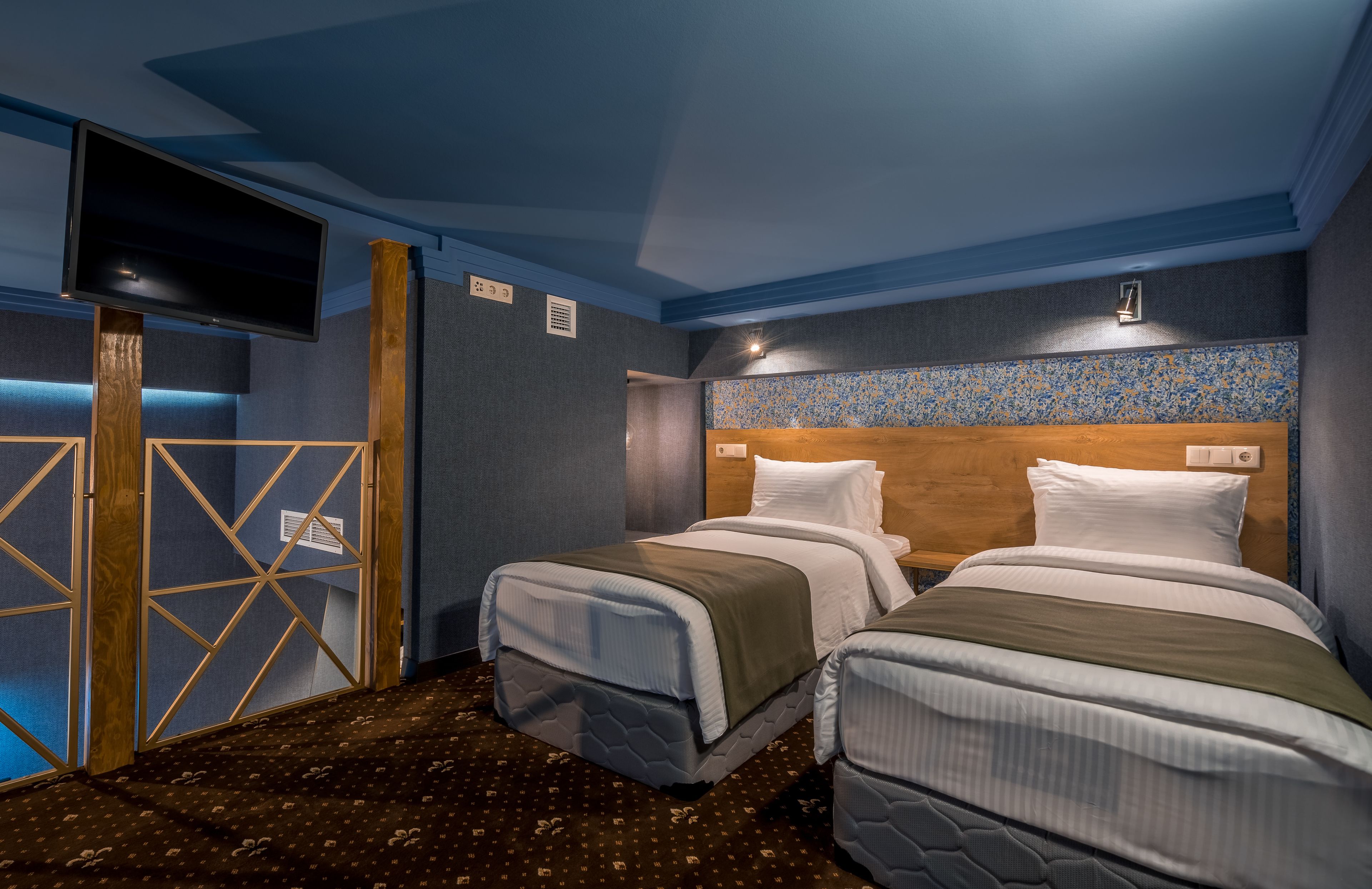 A hotel room with two beds, a TV, and a wooden headboard.