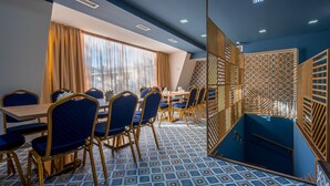 A conference room with a blue and white patterned floor, blue chairs with gold frames, a wooden table, and a large window with curtains. - Hotel Gladius inn (Tbilisi)