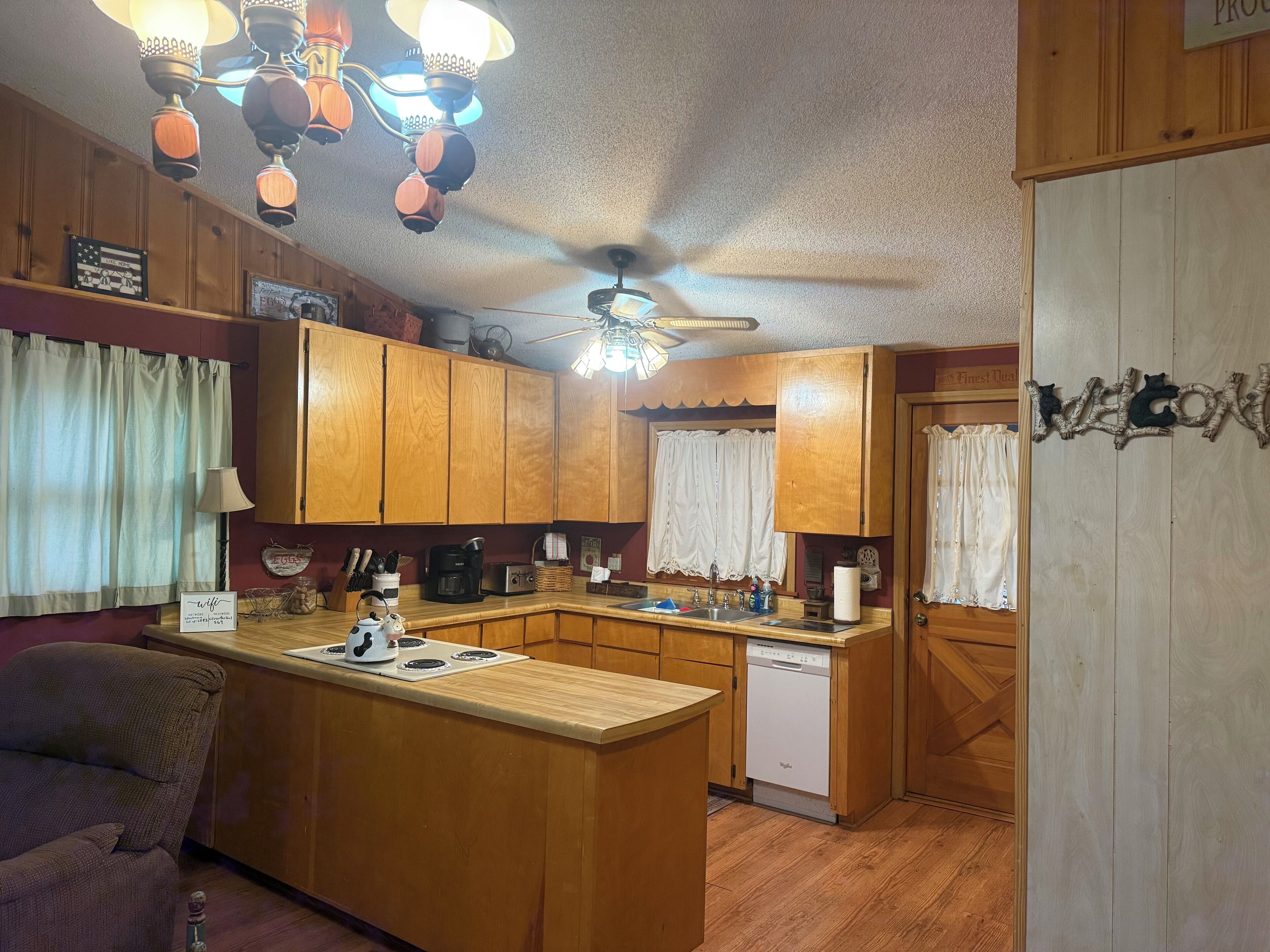 A compact kitchen with wooden cabinets, a central island, a ceiling fan, and a dishwasher.