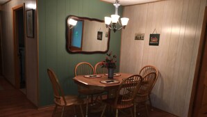 A dining area with a wooden table and chairs, a chandelier, and a mirror on the wall. -  Pet friendly , Motorcycle parking  Hot tub. Close to everything (Maggie Valley)